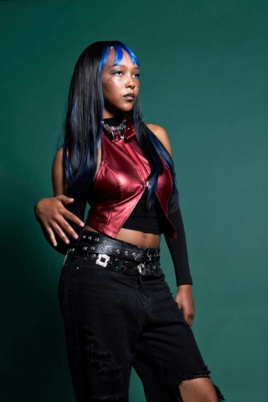 odel with blue-highlighted hair posing in futuristic-inspired fashion during the MAYHEM event.