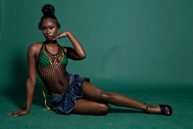 Model in fishnet fashion outfit posing on the floor during the MAYHEM event photoshoot.