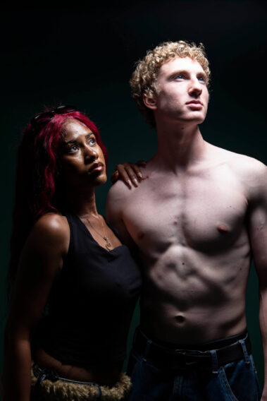 Two models posing dramatically together against a dark backdrop during the MAYHEM event.