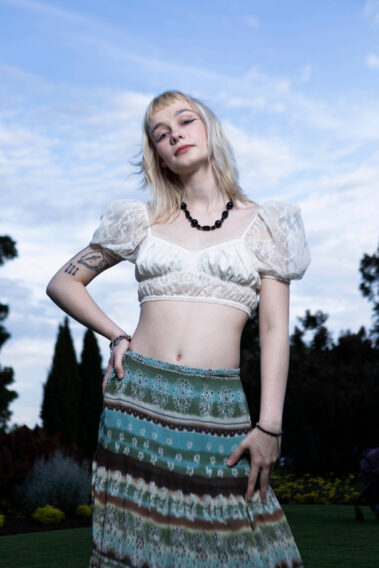 Close-up portrait of madisxnariana wearing a white lace crop top and patterned skirt during an outdoor Garden Party photoshoot.