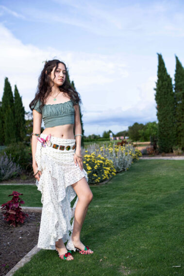 jadyntrann posing in a green crop top and flowing white layered skirt beside blooming flowers at Will Rogers Gardens during the Garden Party photoshoot.