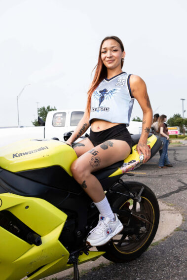 Ice Angels model sitting on a bright yellow Kawasaki sport motorcycle.